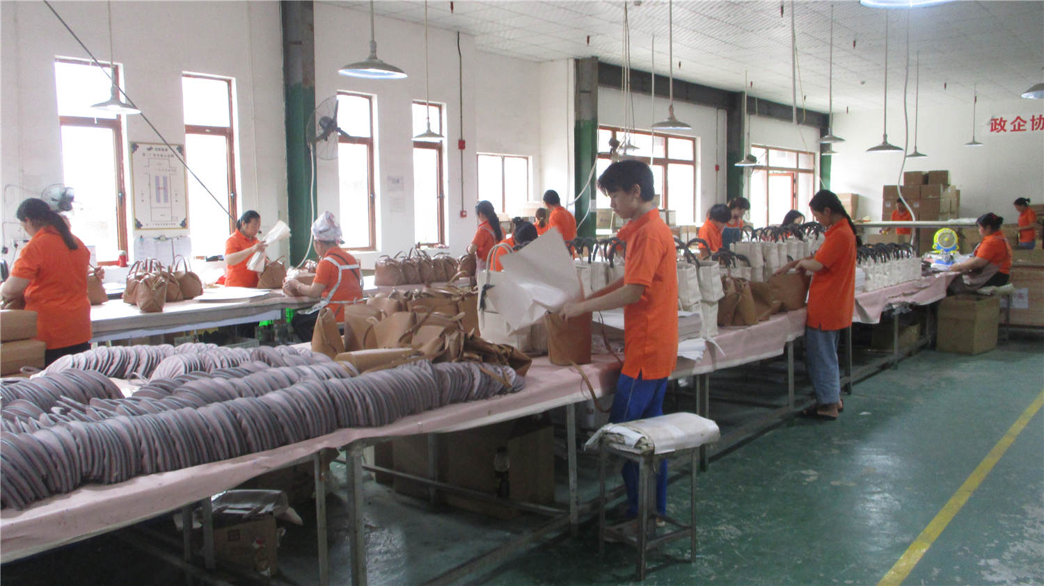 Assembly and packing line with workers inspecting finished bags